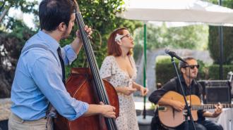 Woman singing while two men play instruments.